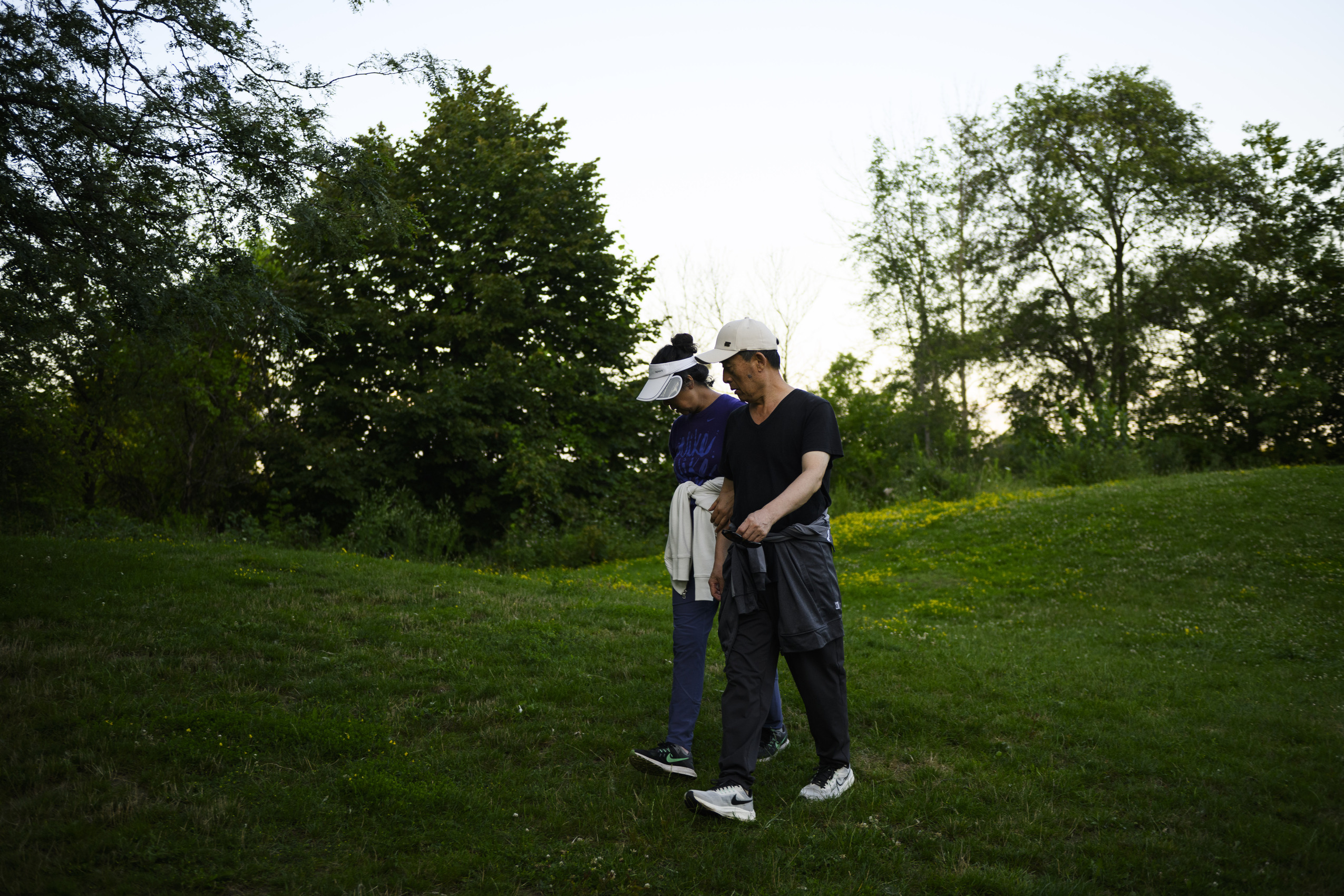 Mimico Creek spill: a middle-aged couple in athletic clothes walks along a green lawn at Humber Bay Park
