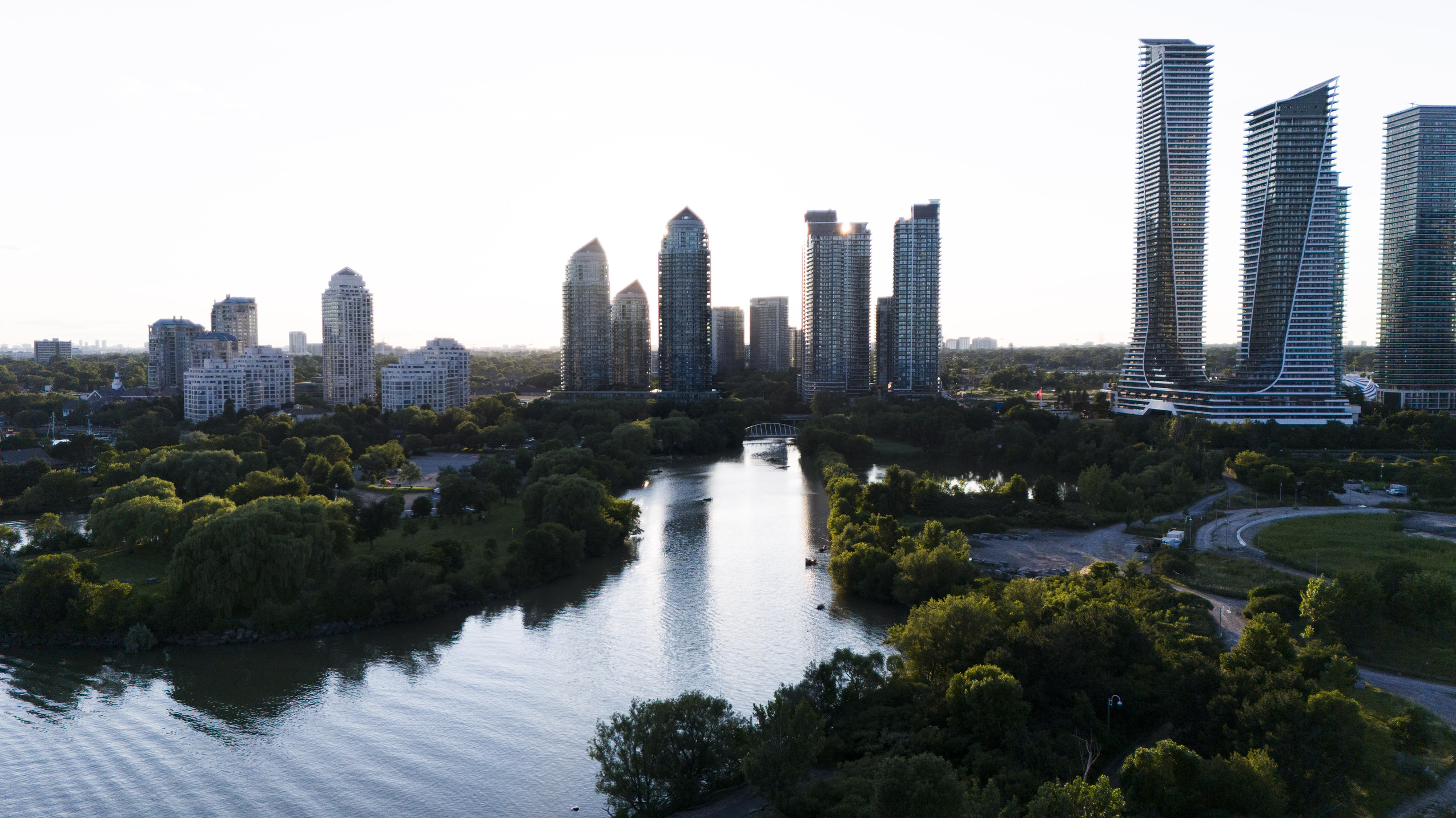 Mimico Creek flows past lush greenery, framed by high-rises just to the north